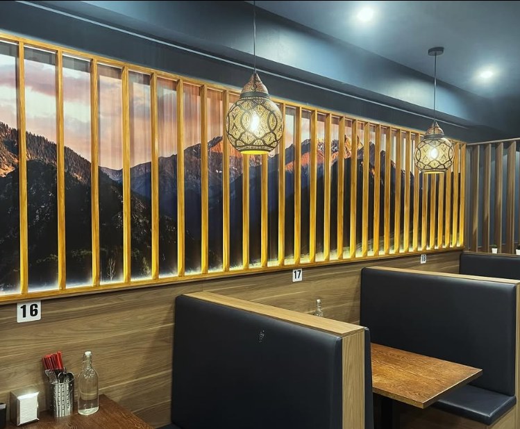 Booths beneath a mountain landscape mural