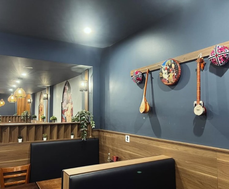 Traditional Uyghur instruments and embroidered caps hanging on a wall