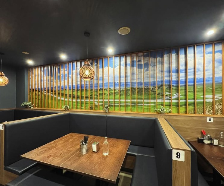 Corner booth under a green grassland mural with lanterns overhead