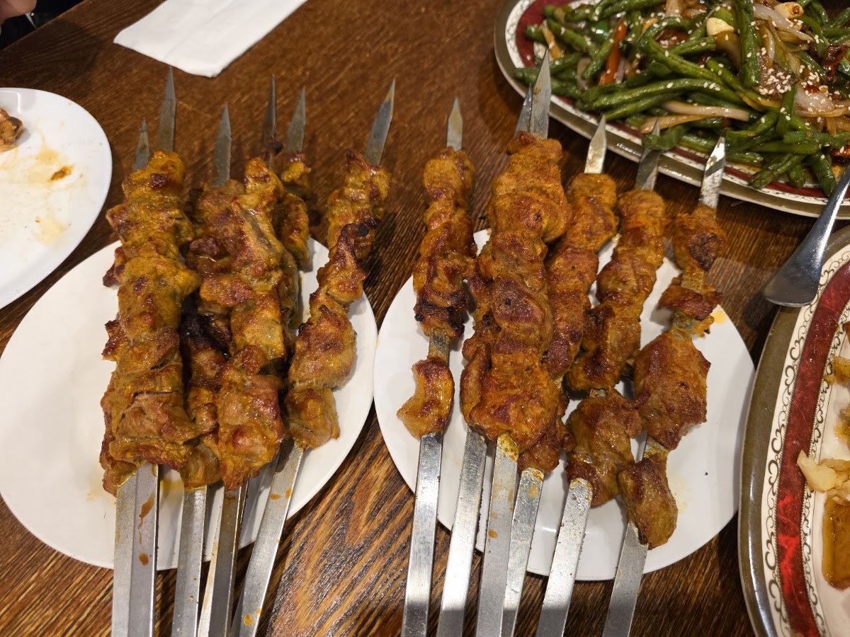 Charcoal lamb skewers and stir-fried green beans on the table at Kaynam